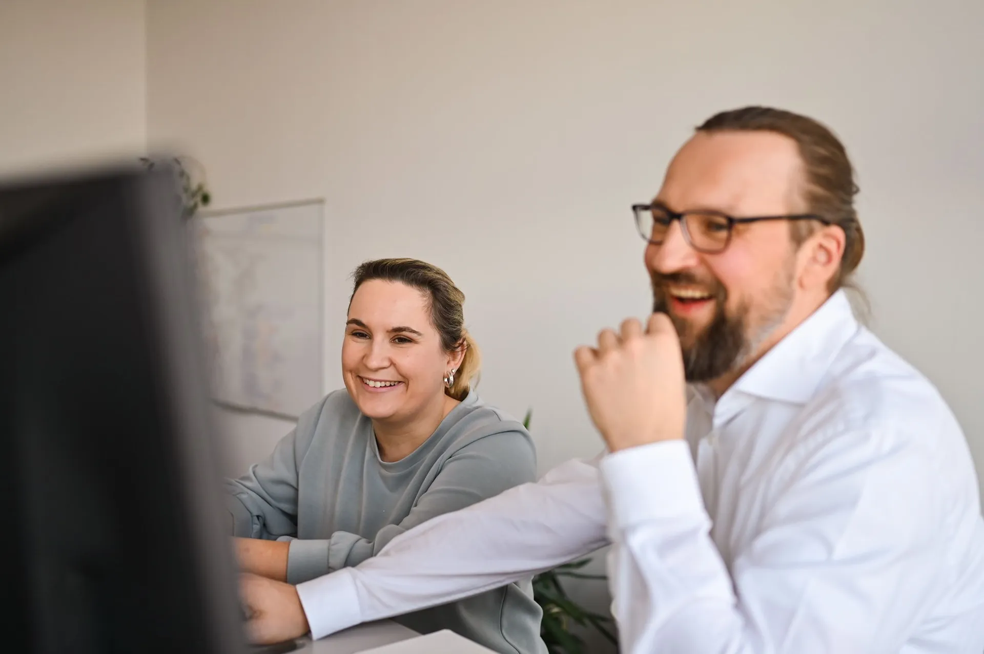 Lächelnde Kollegen bei der Zusammenarbeit im Büro, authentische Teamdarstellung durch Unternehmensfotografie in Nürnberg.