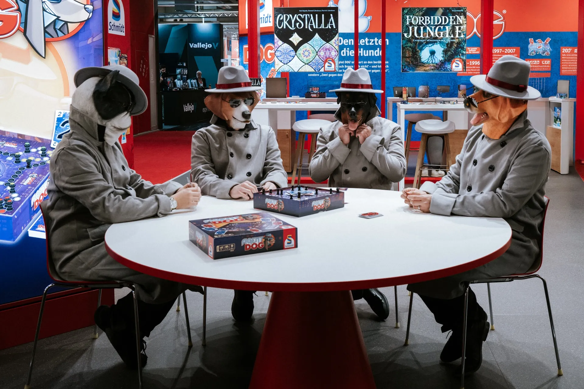 Creative scene at the trade fair booth, four men with dog masks playing board game.