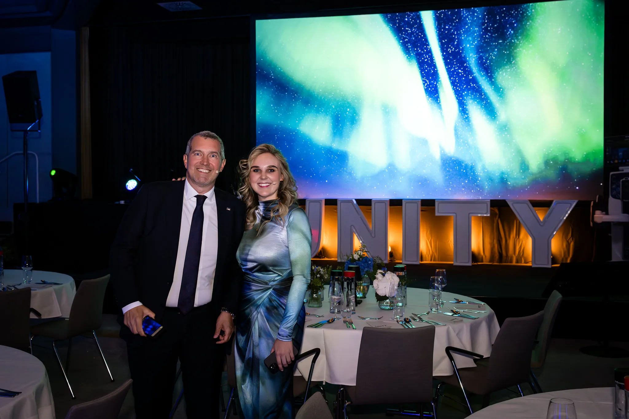 Zwei Gäste posieren nach dem Galadinner vor der UNITY-Bühne