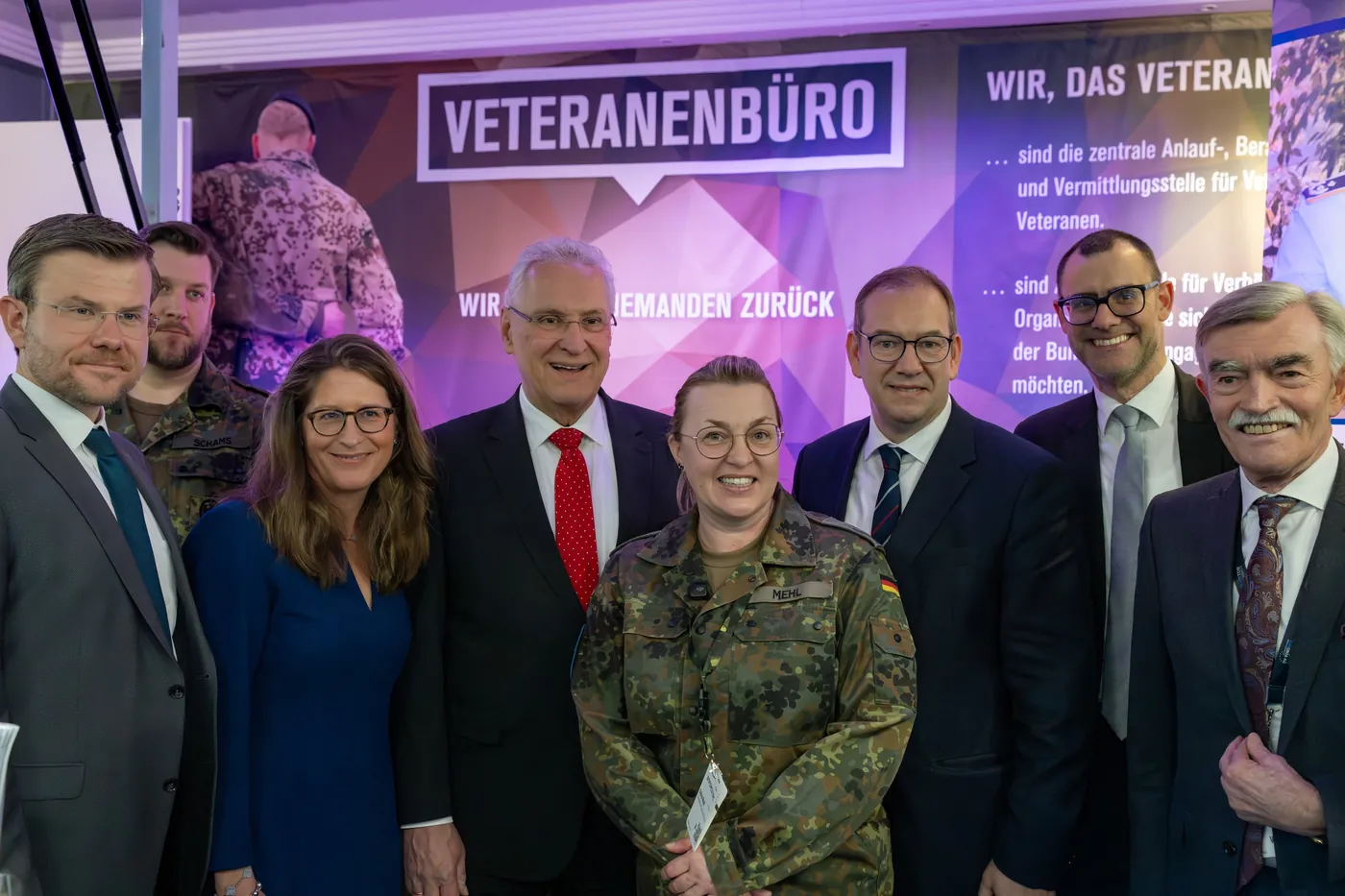Group photo at the “Veteranenbüro” booth with a woman in uniform at Enforce Tac in Nuremberg