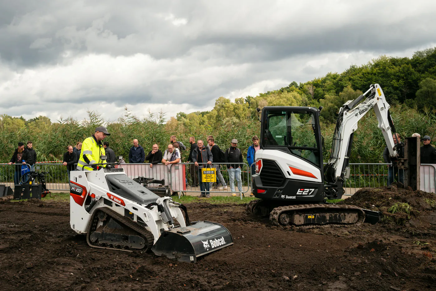 Live demonstration with Bobcat machines working in soil in the outdoor area of GaLaBau in Nuremberg, trade visitors watching from behind the barrier