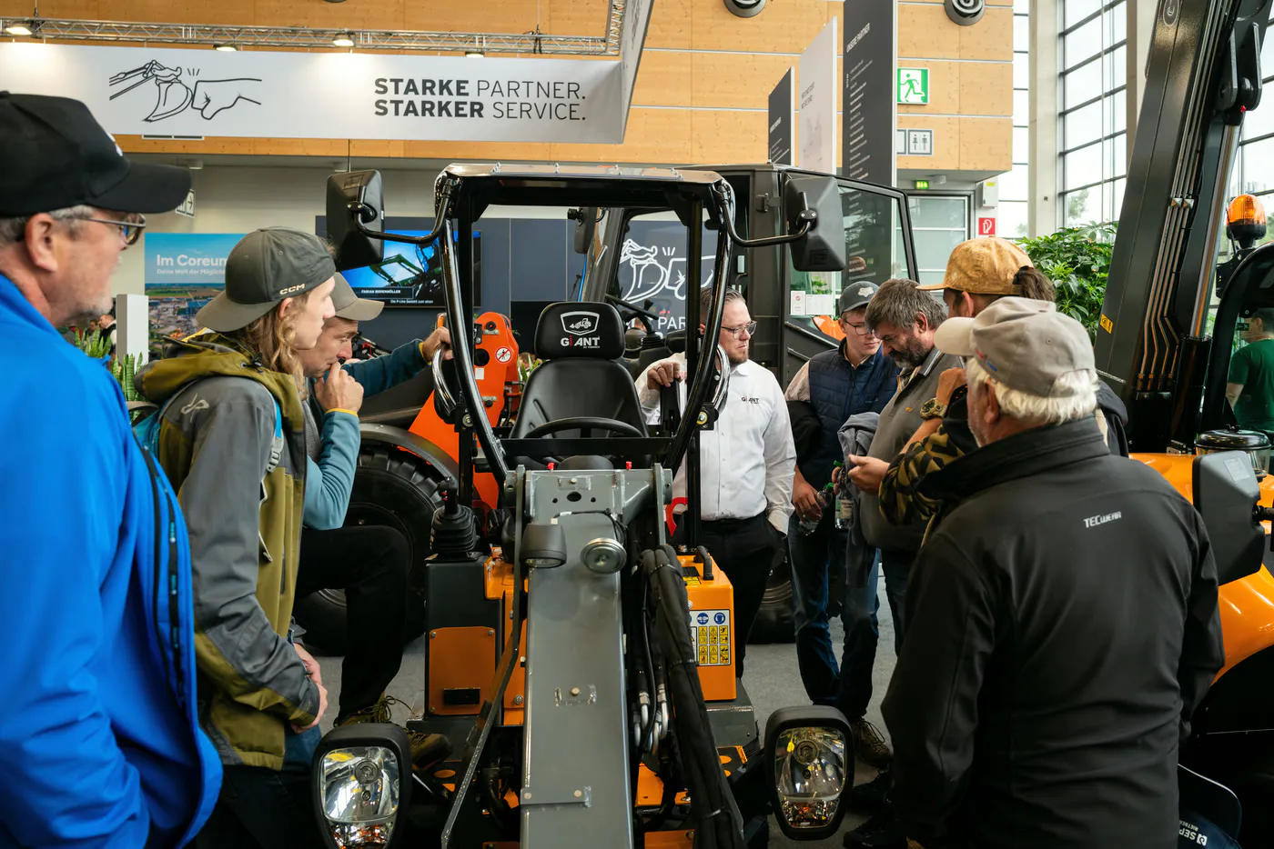 Customer conversation at the stand between staff and trade visitors beside a loader at GaLaBau in Nuremberg