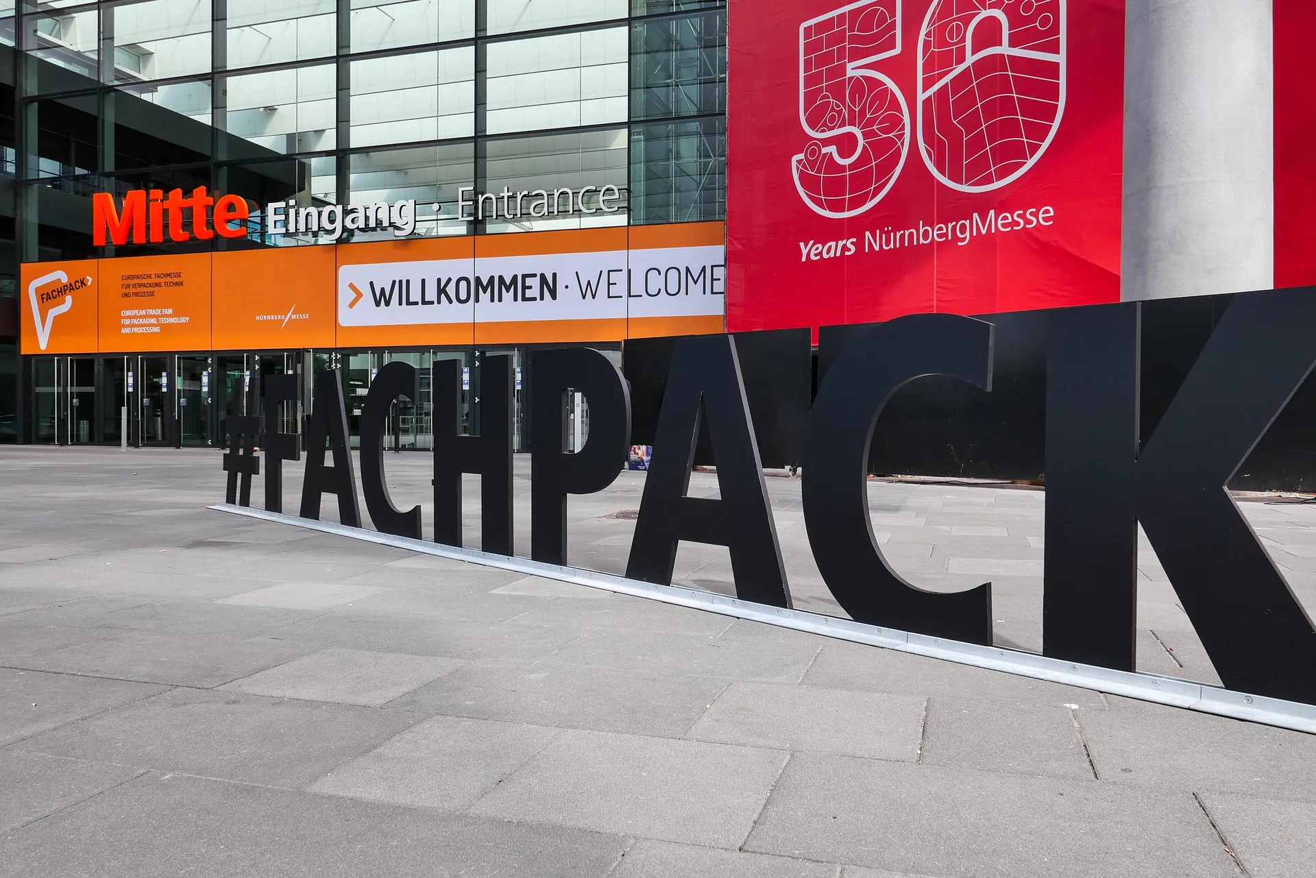 #FACHPACK-Buchstaben vor dem Eingang des Messezentrums Nürnberg mit Banner zu 50 Jahren NürnbergMesse