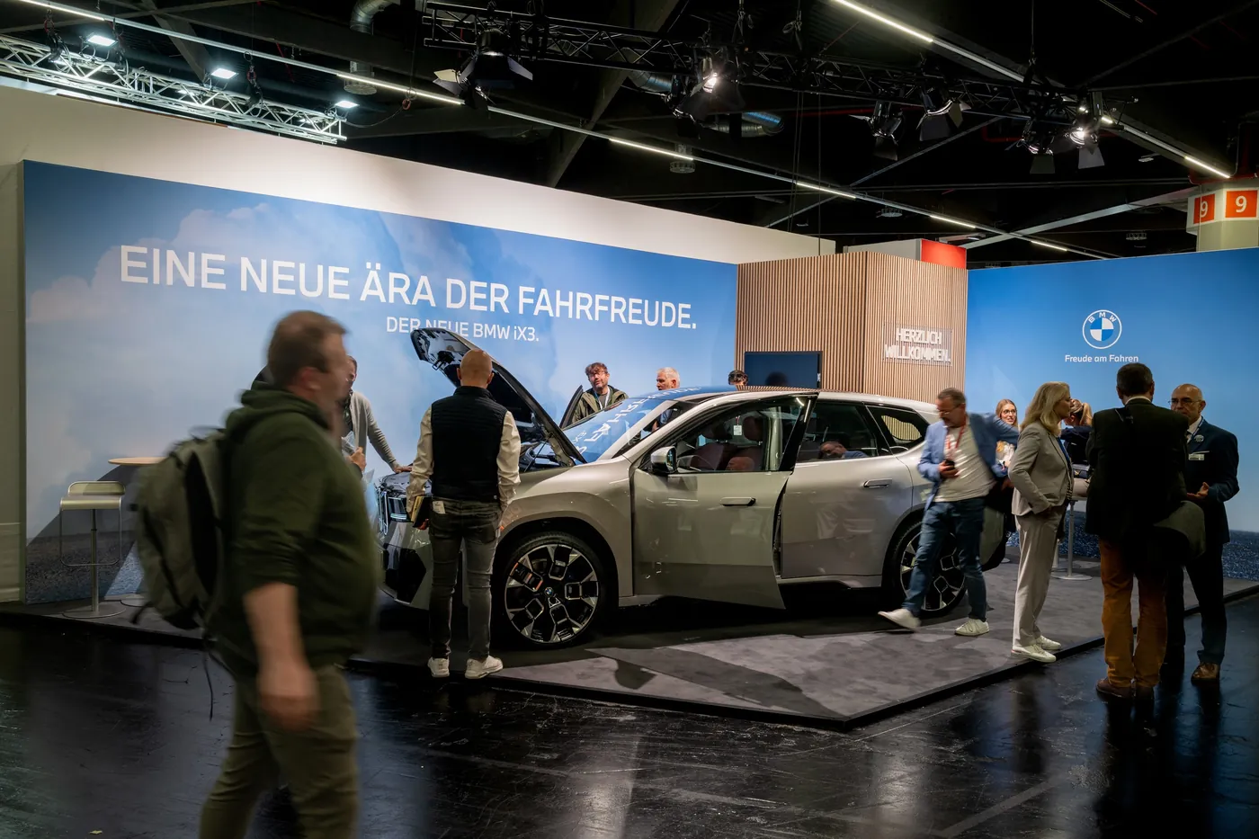 Elektroauto als Exponat am Messestand mit Besuchern