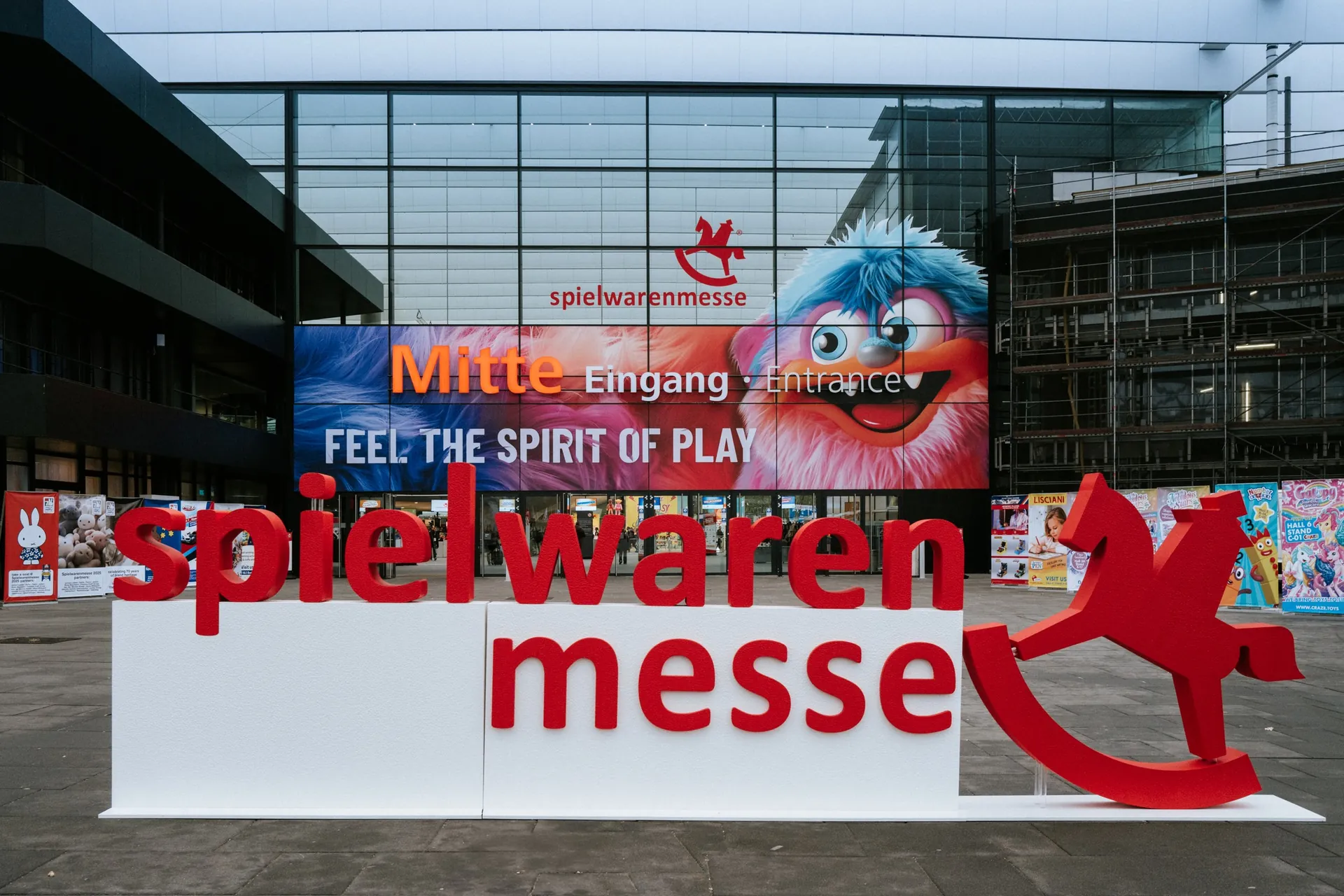 Eingang der Spielwarenmesse in Nürnberg mit großem Spielwarenmesse-Schriftzug und Schaukelpferd-Logo